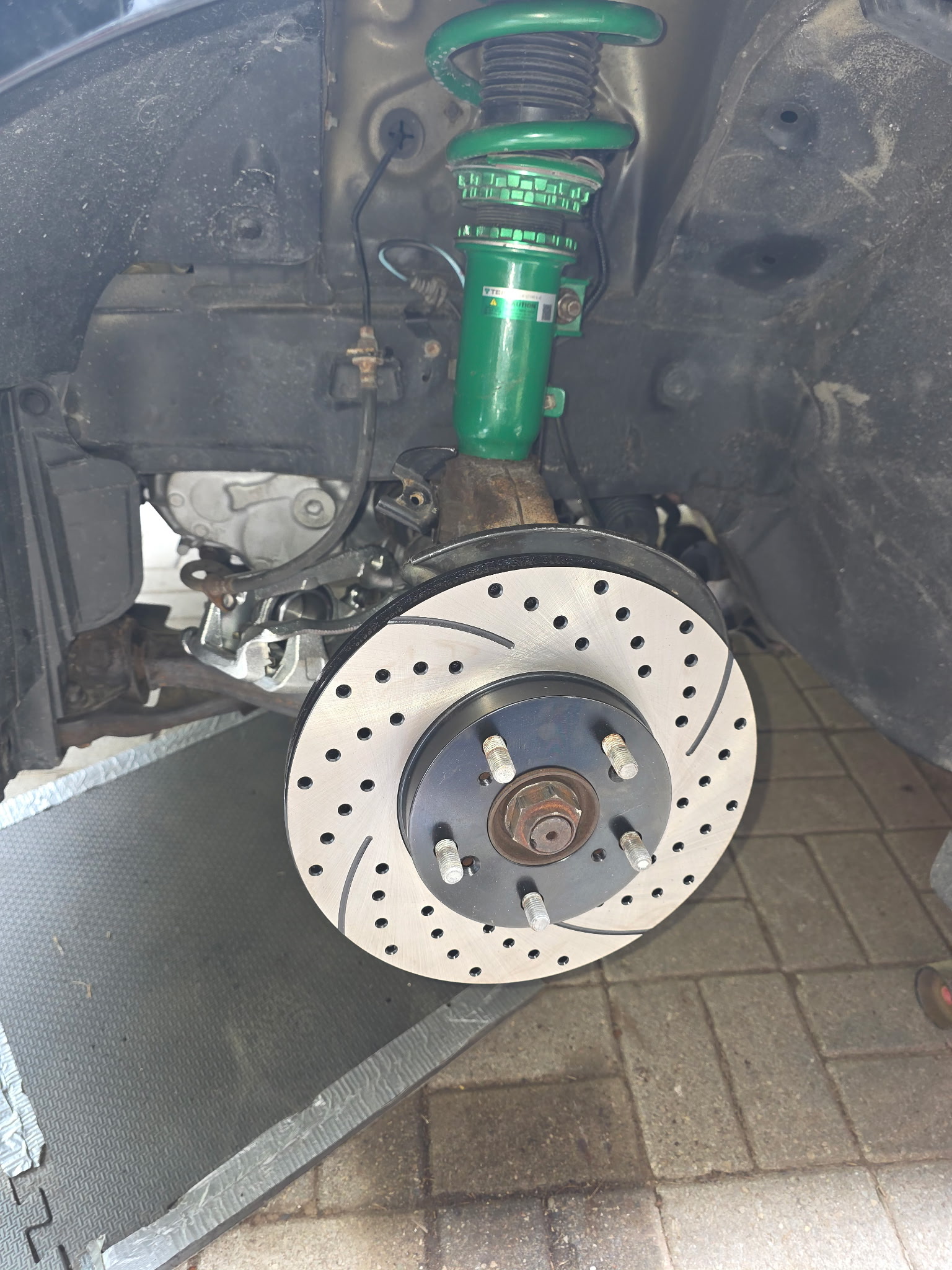 Drilled brake rotor with green TEIN coilover